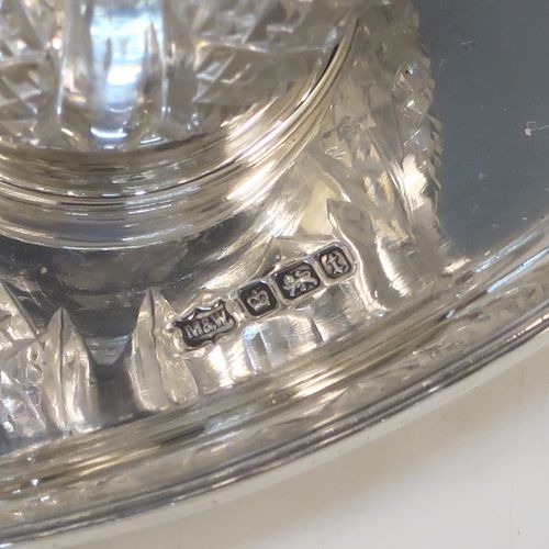 An elegant Antique Sterling Silver single bottle inkstand, with a plain oval boat-shaped body, having an applied reeded border, a single removable cut-crystal ink bottle with hinged lid, and all sitting on four cast flanged feet. This pretty antique silver inkstand was made by Mappin and Webb of Sheffield in 1911. The dimensions of this fine hand-made antique sterling silver inkstand are length 21 cms (8.25 inches), width 9.5 cms (3.75 inches), and it weighs approx. 150g (4.8 troy ounces).  