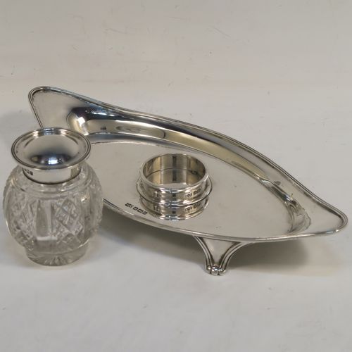 An elegant Antique Sterling Silver single bottle inkstand, with a plain oval boat-shaped body, having an applied reeded border, a single removable cut-crystal ink bottle with hinged lid, and all sitting on four cast flanged feet. This pretty antique silver inkstand was made by Mappin and Webb of Sheffield in 1911. The dimensions of this fine hand-made antique sterling silver inkstand are length 21 cms (8.25 inches), width 9.5 cms (3.75 inches), and it weighs approx. 150g (4.8 troy ounces).  