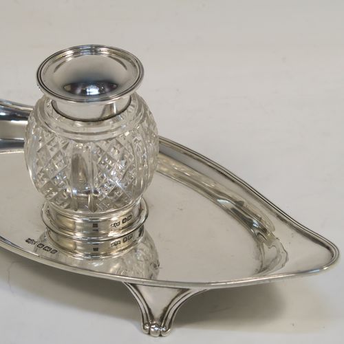 An elegant Antique Sterling Silver single bottle inkstand, with a plain oval boat-shaped body, having an applied reeded border, a single removable cut-crystal ink bottle with hinged lid, and all sitting on four cast flanged feet. This pretty antique silver inkstand was made by Mappin and Webb of Sheffield in 1911. The dimensions of this fine hand-made antique sterling silver inkstand are length 21 cms (8.25 inches), width 9.5 cms (3.75 inches), and it weighs approx. 150g (4.8 troy ounces).  