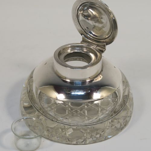 An elegant Antique Sterling Silver and hand-cut crystal inkstand, having a round body with a plain silver top overlay, a hinged lid with an applied reeded border, a plain glass insert, and sitting on a hand-cut hobnail pattern flat base. This very handsome silver and crystal inkstand was made by Henry Miller of Birmingham in 1915. The dimensions of this fine hand-made antique silver and crystal inkstand are height 6 cms (2.3 inches), and diameter 9.5 cms (3.75 inches).  