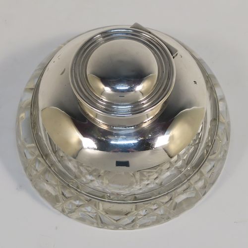 An elegant Antique Sterling Silver and hand-cut crystal inkstand, having a round body with a plain silver top overlay, a hinged lid with an applied reeded border, a plain glass insert, and sitting on a hand-cut hobnail pattern flat base. This very handsome silver and crystal inkstand was made by Henry Miller of Birmingham in 1915. The dimensions of this fine hand-made antique silver and crystal inkstand are height 6 cms (2.3 inches), and diameter 9.5 cms (3.75 inches).  