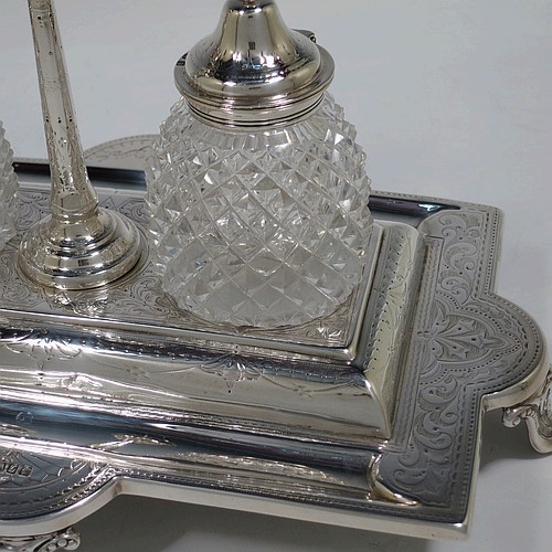 A very pretty and large Antique Victorian Sterling Silver double bottle inkstand, having a rectangular body with a hand-engraved floral and scroll decoration, two pineapple shaped hand-cut crystal removable ink bottles with round domed hinged lids, together with a central taper-stick candle holder, and all sitting on four cast shell and foliate feet. Made by Samuel, Robert, and Charles Belk of Sheffield in 1867. The dimensions of this fine hand-made antique silver double inkstand are length 30.5 cms (12 inches), width 21 cms (8.25 inches), height 18.5 cms (7.25 inches), and it weighs approx. 540g (17.4 troy ounces).   