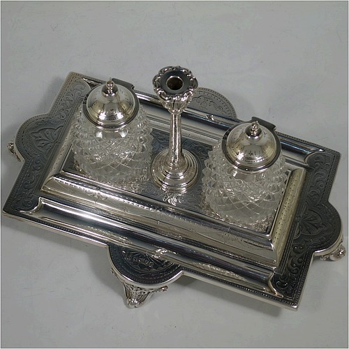 A very pretty and large Antique Victorian Sterling Silver double bottle inkstand, having a rectangular body with a hand-engraved floral and scroll decoration, two pineapple shaped hand-cut crystal removable ink bottles with round domed hinged lids, together with a central taper-stick candle holder, and all sitting on four cast shell and foliate feet. Made by Samuel, Robert, and Charles Belk of Sheffield in 1867. The dimensions of this fine hand-made antique silver double inkstand are length 30.5 cms (12 inches), width 21 cms (8.25 inches), height 18.5 cms (7.25 inches), and it weighs approx. 540g (17.4 troy ounces).   