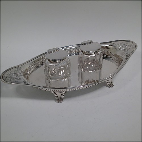 An Antique Edwardian Sterling Silver two bottle double inkstand, with an oval boat-shaped body, having a hand-pierced gallery border and hand-engraved ends with neoclassical style engraving, two removable cut-crystal ink bottles with hinged lids, and all sitting on four cast flanged feet. Made by Hawksworth and Eyre of Sheffield in 1902. The dimensions of this fine hand-made antique sterling silver double inkstand are length 28 cms (11 inches), width 14 cms (5.5 inches), and it weighs approx. 350g (11.2 troy ounces).  