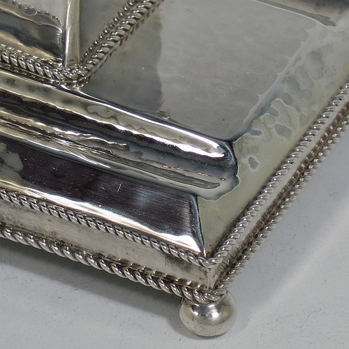 A very pretty Sterling Silver inkstand, in an Arts and Crafts hand-hammered or plenished style, having a single inkwell with a hinged lid and removable glass liner, sitting on a stand with two pen-wells, applied rope-twist borders, and four ball cushion feet. Made in London in 1930. The dimensions of this fine hand-made silver inkstand are height 6.5 cms (2.5 inches), length 11 cms (4.25 inches), width 8 cms (3.25 inches), and it weighs approx. 150g (4.8 troy ounces).    