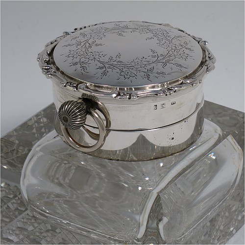 A very handsome and unusual Antique Edwardian Sterling Silver and hand-cut crystal combination inkstand paper weight and clock, having a square body with chamfered upper edges, a plain round mount and a domed hinged lid with hand-engraved floral decoration, the lid enclosing a very fine wind-up clock with black Roman numerals and a white face, all sitting on a flat base with a hand-cut hobnail pattern. Made by Henry Matthews of Birmingham in 1905. The dimensions of this fine antique silver and crystal combination inkstand and clock are height 10 cms (4 inches), and 10 cms (4 inches) square.   