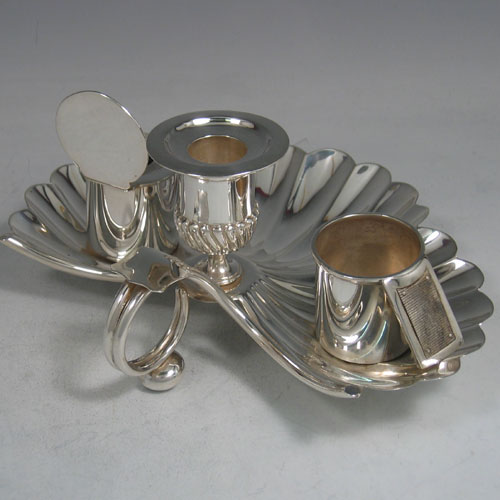 An Antique Victorian Sterling Silver very unusual inkstand, having a shell-style body with hand-chased scallop work, a central candle holder with removable nozzle, a match holder with strike plate, an ink bottle with hinged lid and removable glass liner, a looped carrying handle, and all sitting on three cast cushion feet. Made by Finley & Taylor of London in 1888. The dimensions of this fine hand-made antique inkstand are length 16.5 cms (6.5 inches), width 20 cms (8 inches), height 8.5 cms (3.3 inches), and it weighs approx. 427g (13.8 troy ounces).