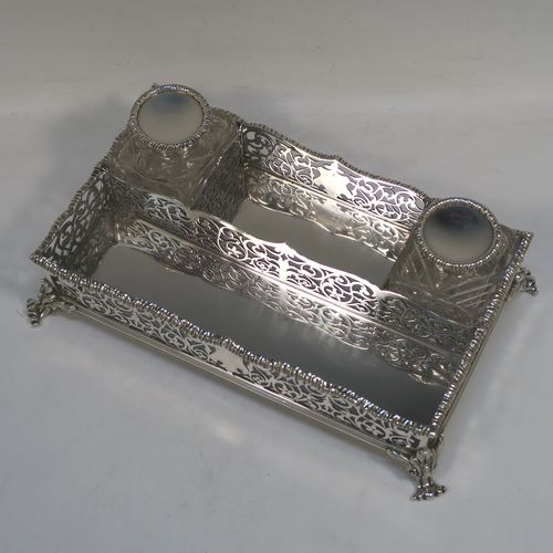 A very pretty Antique Victorian Sterling Silver gallery inkstand, having hand-pierced scroll and floral decoration, applied gadroon borders, two removable crystal inkwells with hinged lids, and all sitting on four cast foliate feet. This beautiful antique silver galleried inkstand was made by William J. Barnard of London in 1886. The dimensions of this fine hand-made silver inkstand are length 22 cms (8.75 inches), width 13 cms (5 inches), height 8 cms (3 inches), and it weighs approx. 620g (20 troy ounces).  