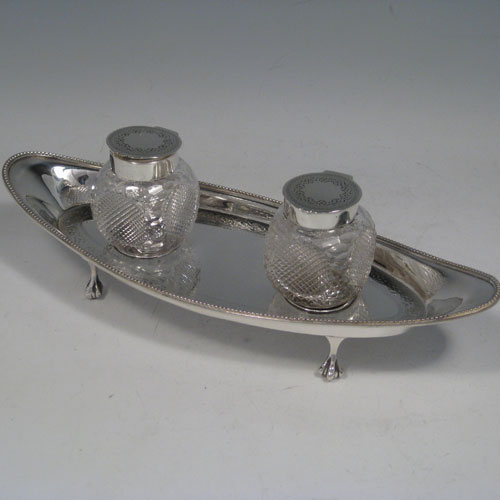    Antique Victorian sterling silver oval inkstand with two removable cut-crystal ink bottles. With bead edge, claw & ball feets, and hand-engraved decoration. Made by Martin & Hall of Sheffield in 1898. Length 24 cms (9.5 inches), width 9 cms (3.5 inches), height 8 cms (3 inches). 