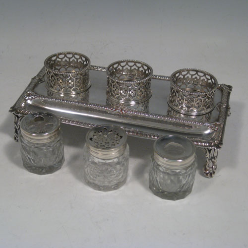    Antique Georgian sterling silver inkstand, having a rectangular body with gadroon and shell border, single pen-well, three hand-cut crystal bottles held within pierced inkwell galleries, all sitting on four cast foliate feet. The glass inkwells are for pens (quills), pounce, and ink. Made by William Plummer of London in 1772. Length 18 cms (7.25 inches), width 11 cms (4.25 inches), height 7.5 cms (3 inches). Weight approx. 240g (7.7 troy ounces).