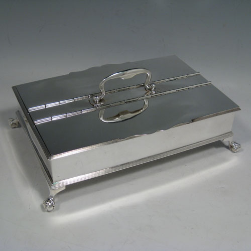 Sterling silver Treasury inkstand, having a rectanuglar body, with two hinged lids covering two compartments, with one side containing two crystal and silver inkwells, a cast scroll carrying handle, and all sitting on four cast claw and ball feet. Made by the Barnard Brothers of London in 1913. Length 25 cms (9.75 inches), height 9 cms (3.5 inches), width 16.5 cms (6.5 inches). Total weight approx. 1,354g (43.7 ounces).