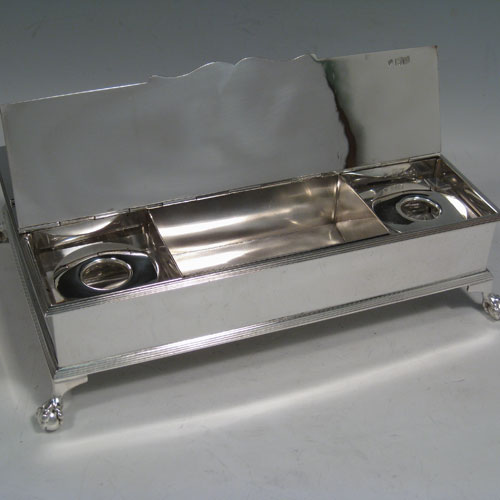 Sterling silver Treasury inkstand, having a rectanuglar body, with two hinged lids covering two compartments, with one side containing two crystal and silver inkwells, a cast scroll carrying handle, and all sitting on four cast claw and ball feet. Made by the Barnard Brothers of London in 1913. Length 25 cms (9.75 inches), height 9 cms (3.5 inches), width 16.5 cms (6.5 inches). Total weight approx. 1,354g (43.7 ounces).