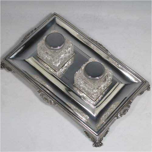 An Antique Victorian Sterling Silver inkstand, having a rectangular body with gadroon and shell border, two square hand-cut crystal removable ink bottles with round hinged lids, all sitting on four cast foliate and claw feet. Made by Henry Wilkinson & Co., of London in 1899. The dimensions of this fine hand-made antique silver double inkstand are length 25 cms (10 inches), width 16 cms (6.3 inches), height 8 cms (3.25 inches), and it weighs approx. 395g (12.6 troy ounces).