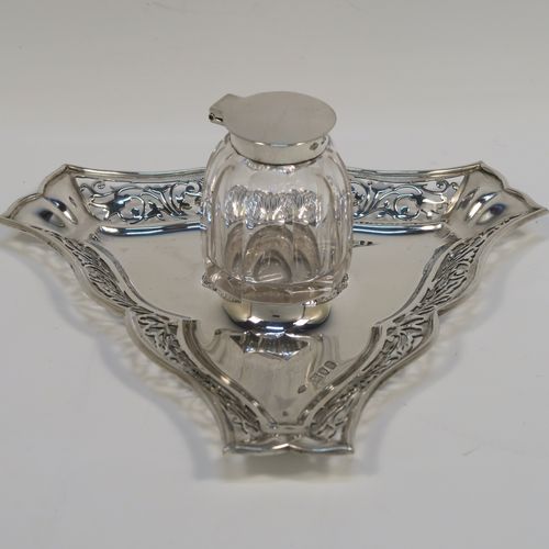 A very pretty and unusual Antique Edwardian Sterling Silver galleried double inkstand, having a triangular body with three hand-pierced scroll-work gallery sides, a removable central single crystal inkwell with a hinged lid, all sitting on a flat base. This beautiful silver inkstand was made by Sibray Hall and Co., of London in 1903. The dimensions of this fine hand-made antique silver  inkstand are width 17 cms (6.75 inches), height 6 cms (2.3 inches), and it weighs approx. 130g (4.2 troy ounces).   