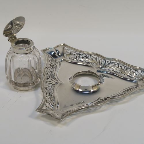 A very pretty and unusual Antique Edwardian Sterling Silver galleried double inkstand, having a triangular body with three hand-pierced scroll-work gallery sides, a removable central single crystal inkwell with a hinged lid, all sitting on a flat base. This beautiful silver inkstand was made by Sibray Hall and Co., of London in 1903. The dimensions of this fine hand-made antique silver  inkstand are width 17 cms (6.75 inches), height 6 cms (2.3 inches), and it weighs approx. 130g (4.2 troy ounces).   