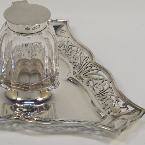 A very pretty and unusual Antique Edwardian Sterling Silver galleried double inkstand, having a triangular body with three hand-pierced scroll-work gallery sides, a removable central single crystal inkwell with a hinged lid, all sitting on a flat base. This beautiful silver inkstand was made by Sibray Hall and Co., of London in 1903. The dimensions of this fine hand-made antique silver  inkstand are width 17 cms (6.75 inches), height 6 cms (2.3 inches), and it weighs approx. 130g (4.2 troy ounces).   