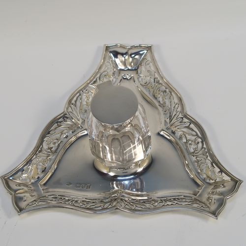 A very pretty and unusual Antique Edwardian Sterling Silver galleried double inkstand, having a triangular body with three hand-pierced scroll-work gallery sides, a removable central single crystal inkwell with a hinged lid, all sitting on a flat base. This beautiful silver inkstand was made by Sibray Hall and Co., of London in 1903. The dimensions of this fine hand-made antique silver  inkstand are width 17 cms (6.75 inches), height 6 cms (2.3 inches), and it weighs approx. 130g (4.2 troy ounces).   