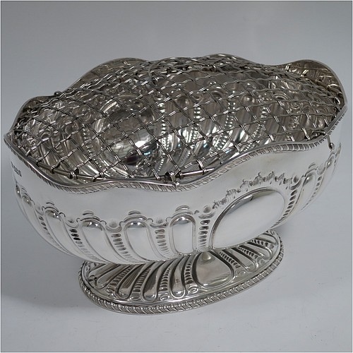 An Antique Victorian Sterling Silver flower Jardiniere, having an oval body, with an applied shaped gadroon border and hand-chased fluted decoration, with vacant round cartouches either side, and sitting on a matching pedestal foot. Made by Henry Atkins of Sheffield in 1892. The dimensions of this fine hand-made antique silver Jardiniere for flowers are length 20 cms (8 inches), width 15 cms (6 inches), height 11 cms (4.25 inches), and it weighs approx. 373g (12 troy ounces). Please note that this piece has its own hand-made to fit silver-plated rose grill. 