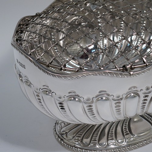 An Antique Victorian Sterling Silver flower Jardiniere, having an oval body, with an applied shaped gadroon border and hand-chased fluted decoration, with vacant round cartouches either side, and sitting on a matching pedestal foot. Made by Henry Atkins of Sheffield in 1892. The dimensions of this fine hand-made antique silver Jardiniere for flowers are length 20 cms (8 inches), width 15 cms (6 inches), height 11 cms (4.25 inches), and it weighs approx. 373g (12 troy ounces). Please note that this piece has its own hand-made to fit silver-plated rose grill. 