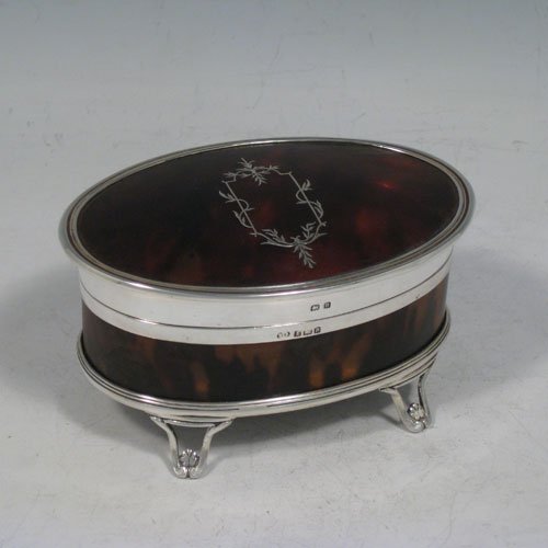 Sterling silver and tortoise-shell very pretty jewelery box, having an oval-shaped body, a hinged lid with inlaid cartouche, applied reeded borders, a light brown velvet-lined interior, and sitting on four foliate feet. Made in Birmingham in 1926. The dimensions of this fine hand-made silver and tortoise-shell jewelery box are length 11.5 cms (4.5 inches), width 8 cms (3 inches), and height 6 cms (2.3 inches).    