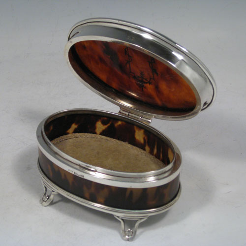 Sterling silver and tortoise-shell very pretty jewelery box, having an oval-shaped body, a hinged lid with inlaid cartouche, applied reeded borders, a light brown velvet-lined interior, and sitting on four foliate feet. Made in Birmingham in 1926. The dimensions of this fine hand-made silver and tortoise-shell jewelery box are length 11.5 cms (4.5 inches), width 8 cms (3 inches), and height 6 cms (2.3 inches).    