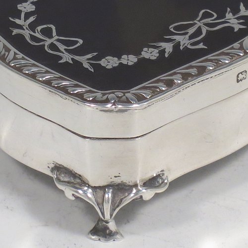 A very pretty Antique Edwardian Sterling Silver and tortoise-shell jewellery box, having a shaped rectangular body, a tortoise-shell hinged lid with in-laid flowers and ribbon bows, an applied gadroon border, a dark blue velvet-lined interior, and sitting on four cast foliate legs. Made by Henry Miller of Birmingham in 1910. The dimensions of this fine hand-made antique silver and tortoise-shell jewelery box are length 7 cms (2.75 inches), width 5.5 cms (2.25 inches), and height 3 cms (1.25 inches).   