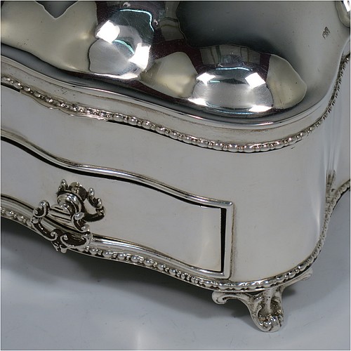 An Antique Edwardian Sterling Silver large jewellery box, having a rectangular shaped casket style body with rounded corners and applied pearl and bead borders, a plain domed hinged lid covering a velvet-lined interior, a pull-out drawer with a cast swing handle, and all sitting on four cast foliate feet. Made by Nathan and Hayes of Chester in 1907. The dimensions of this fine hand-made antique silver jewellery box are length 13.5 cms (5.3 inches), width 11 cms (4.3 inches), and height 11 cms (4.3 inches).   