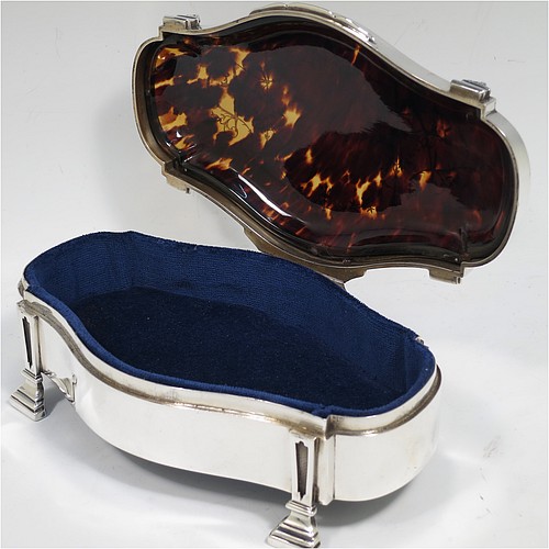 A very pretty and large Antique Sterling Silver and tortoise-shell jewellery box, having an oval shaped body, a tortoise-shell hinged lid with in-laid flowers and ribbon bows, a dark blue velvet-lined interior, and sitting on four cast stepped and columnar style feet. Made by William Comyns of London in 1913. The dimensions of this fine hand-made antique silver and tortoise-shell jewelery box are length 20 cms (8 inches), width 12.5 cms (5 inches), and height 7 cms (2.75 inches).    