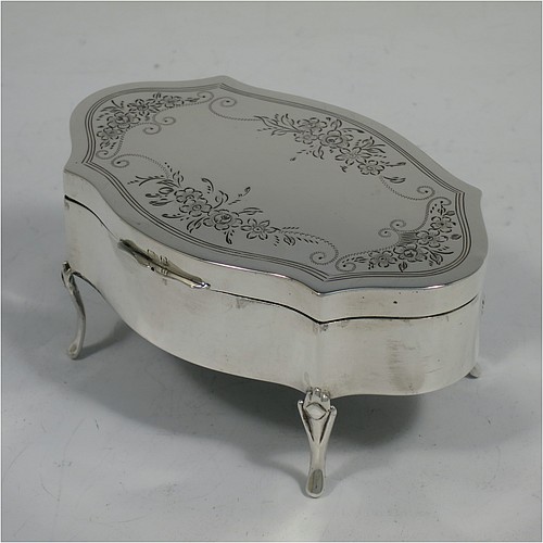 A very pretty Antique Sterling Silver jewelery box, having an oval-shaped body with straight sides, a flat hinged lid with hand-engraved floral decoration, a gold gilt and dark green velvet-lined interior, and all sitting on four cast foliate feet. Made by Henry Matthews of Birmingahm in 1912. The dimensions of this fine hand-made antique silver jewellery box are length 10cms (4 inches), width 7cms (2.75 inches), and height 5 cms (2 inches)    