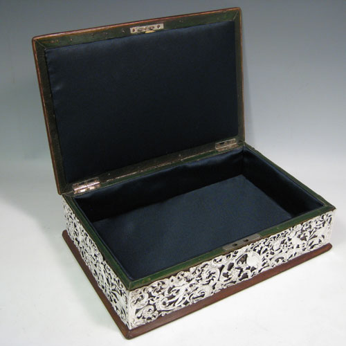 Antique Victorian sterling silver jewellery box, having a hinged lid, a satin-lined interior, a rectangular wooden body with hand-pierced silver panels which are pinned to the wood, with cherubs, birds, faces, and styalised floral decoration. Made by William Comyns of London in 1898. Length 31 cms (12.25 inches), height 8.5 cms (3.3 inches), width 21 cms (8.25 inches).