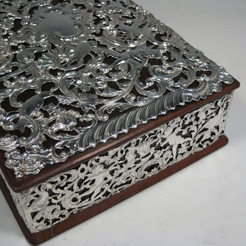 Antique Victorian sterling silver jewellery box, having a hinged lid, a satin-lined interior, a rectangular wooden body with hand-pierced silver panels which are pinned to the wood, with cherubs, birds, faces, and styalised floral decoration. Made by William Comyns of London in 1898. Length 31 cms (12.25 inches), height 8.5 cms (3.3 inches), width 21 cms (8.25 inches).