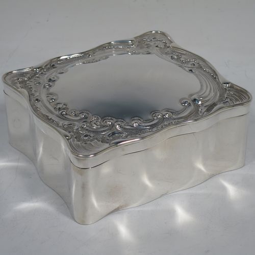 A very pretty Antique Edwardian Sterling Silver jewellery box, having a rectangular shaped body, a hinged lid with hand-chased floral and scroll decoration, a green satin and velvet-lined interior with a slotted ring compartment, and all sitting on a flat base. Made Elkington and Co., of Birmingham in 1909. The dimensions of this fine hand-made antique silver jewelery box are length 11 cms (4.3 inches), width 10 cms (4 inches), and height 4.5 cms (1.75 inches).   