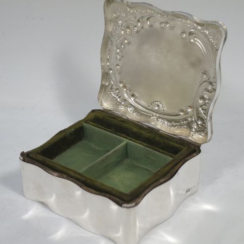 A very pretty Antique Edwardian Sterling Silver jewellery box, having a rectangular shaped body, a hinged lid with hand-chased floral and scroll decoration, a green satin and velvet-lined interior with a slotted ring compartment, and all sitting on a flat base. Made Elkington and Co., of Birmingham in 1909. The dimensions of this fine hand-made antique silver jewelery box are length 11 cms (4.3 inches), width 10 cms (4 inches), and height 4.5 cms (1.75 inches).   