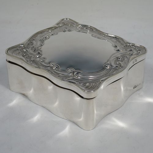 A very pretty Antique Edwardian Sterling Silver jewellery box, having a rectangular shaped body, a hinged lid with hand-chased floral and scroll decoration, a green satin and velvet-lined interior with a slotted ring compartment, and all sitting on a flat base. Made Elkington and Co., of Birmingham in 1909. The dimensions of this fine hand-made antique silver jewelery box are length 11 cms (4.3 inches), width 10 cms (4 inches), and height 4.5 cms (1.75 inches).   