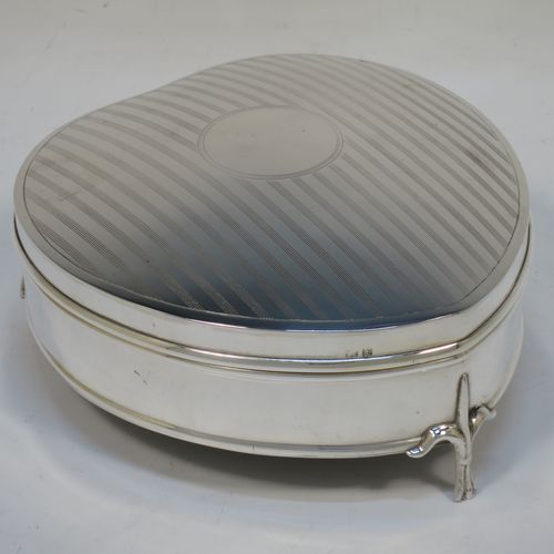 A pretty Antique Sterling Silver jewellery box, having a heart-shaped body with straight sides, a a hinged lid with reeded decoration and a central round vacant cartouche, a gold-gilt and dark-blue velvet-lined interior, and all sitting on three cast fleur-de-lis legs. Made by Saunders and Shepherd of Birmingham in 1918. The dimensions of this fine hand-made antique silver  jewelery box are length 12 cms (4.75 inches), width 11 cms (4.3 inches), and height 5 cms (2 inches).  