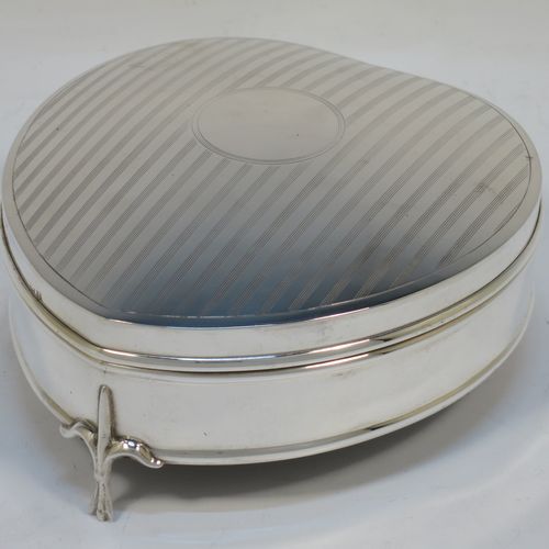 A pretty Antique Sterling Silver jewellery box, having a heart-shaped body with straight sides, a a hinged lid with reeded decoration and a central round vacant cartouche, a gold-gilt and dark-blue velvet-lined interior, and all sitting on three cast fleur-de-lis legs. Made by Saunders and Shepherd of Birmingham in 1918. The dimensions of this fine hand-made antique silver  jewelery box are length 12 cms (4.75 inches), width 11 cms (4.3 inches), and height 5 cms (2 inches).  