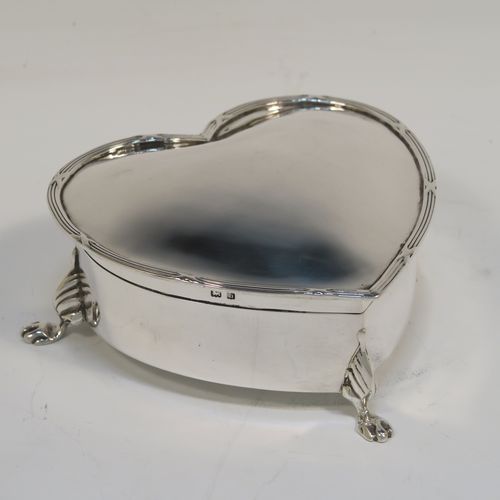 A pretty Antique Edwardian Sterling Silver jewellery box, having a plain heart-shaped body with straight sides, a hinged lid with an applied ribbon and reed border, and dark-blue velvet-lined interior, and all sitting on three cast lions-paw feet. This beautiful heart-shaped silver jewelery box was made by T. H. Hazlewood of Birmingham in 1907. The dimensions of this fine hand-made antique silver jewelery box are length 10 cms (4 inches), width 11 cms (4.3 inches), and height 4 cms (1.5 inches).  