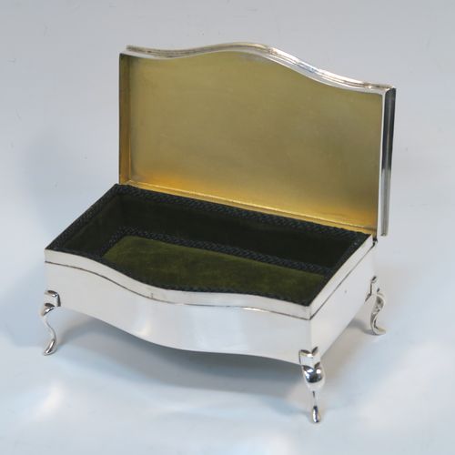 A very handsome Antique Sterling Silver jewelery box, having a dressing table style plain rectangular bow-fronted body, a plain and slightly domed hinged lid with an applied egg and dart border, a gold gilt and green velvet-lined interior, and all sitting on four cabriolet feet. This elegant antique silver jewellery box was made by Synyer and Beddoes of Birmingham in 1913. The dimensions of this fine hand-made antique silver jewellery box are width 14cms (5.5 inches), depth 7.5cms (3 inches), and height 6 cms (2.25 inches)   