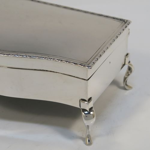 A very handsome Antique Sterling Silver jewelery box, having a dressing table style plain rectangular bow-fronted body, a plain and slightly domed hinged lid with an applied egg and dart border, a gold gilt and green velvet-lined interior, and all sitting on four cabriolet feet. This elegant antique silver jewellery box was made by Synyer and Beddoes of Birmingham in 1913. The dimensions of this fine hand-made antique silver jewellery box are width 14cms (5.5 inches), depth 7.5cms (3 inches), and height 6 cms (2.25 inches)   