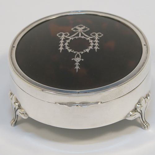 A very pretty Antique Sterling Silver and tortoise-shell jewellery box, having a plain round body, an in-laid tortoise-shell hinged lid, a cream coloured velvet-lined base, and sitting on three cast foliate feet. This beautiful silver and tortoise shell jewellery box was made by Synyer and Beddoes of Birmingham in 1919. The dimensions of this fine hand-made antique silver jewelery box are diameter 9 cms (3.5 inches), and height 4.5 cms (1.75 inches).   