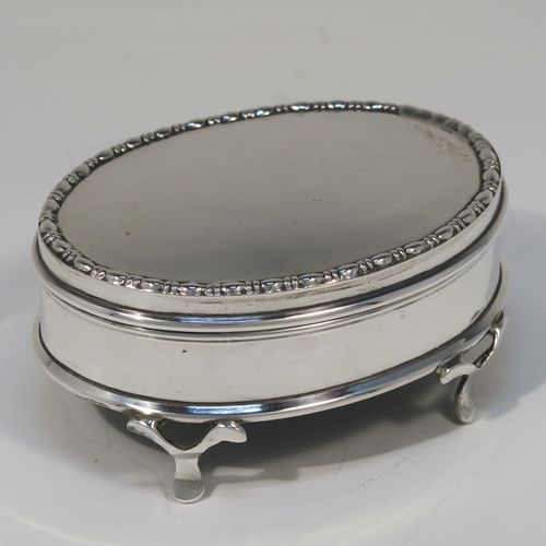 A very elegant Antique Sterling Silver jewelery box, having a plain oval-shaped body with straight sides, a slightly domed hinged lid with an applied pear and bead top border, a gold gilt and green velvet-lined interior, and all sitting on four flanged feet. This handsome silver jewellery box was made by Charles Edwards of London in 1918. The dimensions of this fine hand-made antique silver jewellery box are width 9 cms (3.5 inches), depth 6.5 cms (2.5 inches), and height 4.5 cms (1.75 inches)   