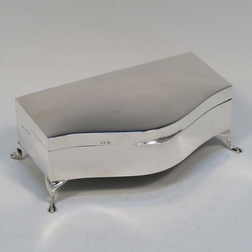 A very handsome Antique Sterling Silver jewelery box, having a dressing table style plain rectangular bow-fronted body, a plain and slightly domed hinged, a gold gilt and dark blue satin-lined interior, and all sitting on four cabriolet feet. This elegant antique silver jewellery box was made by Deakin and Francis of Birmingham in 1919. The dimensions of this fine hand-made antique silver jewellery box are width 13 cms (5 inches), depth 8 cms (3 inches), and height 5 cms (2 inches)  