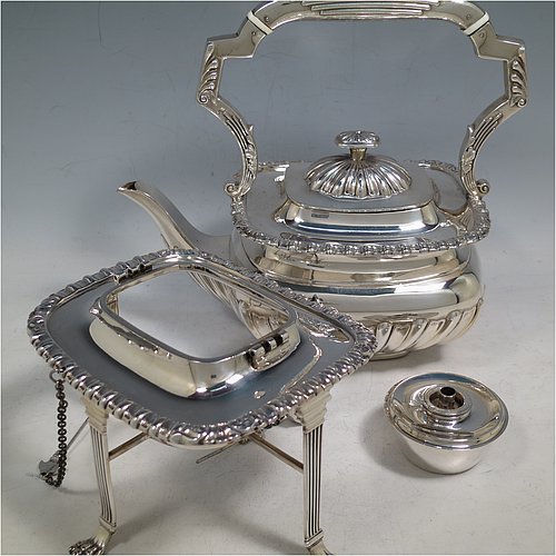 An Antique Victorian Sterling Silver tea kettle on a burner stand, having a Georgian Regency style rectangular bellied body with applied gadroon & shell borders and hand-chased fluted decoration, together with a hinged domed lid, an insulated silver handle and finial, and sitting on an original burner stand with four fluted lions-paw feet. Made by Charles Boyton of London in 1900. The dimensions of this fine hand-made antique silver kettle are length 24 cms (9.5 inches), height 33 cms (13 inches), width 15 cms (6 inches), and the total weight is approx. 1,056g (34 troy ounces).    