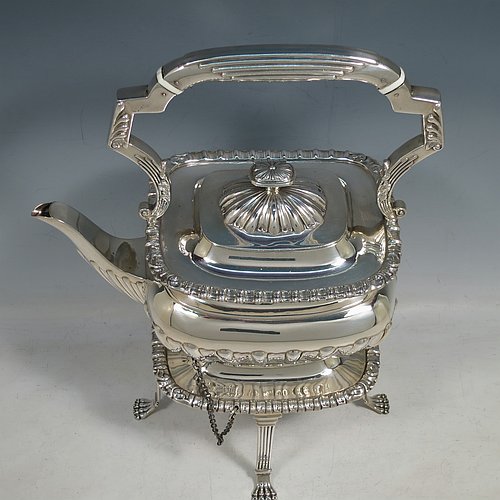 An Antique Victorian Sterling Silver tea kettle on a burner stand, having a Georgian Regency style rectangular bellied body with applied gadroon & shell borders and hand-chased fluted decoration, together with a hinged domed lid, an insulated silver handle and finial, and sitting on an original burner stand with four fluted lions-paw feet. Made by Charles Boyton of London in 1900. The dimensions of this fine hand-made antique silver kettle are length 24 cms (9.5 inches), height 33 cms (13 inches), width 15 cms (6 inches), and the total weight is approx. 1,056g (34 troy ounces).    