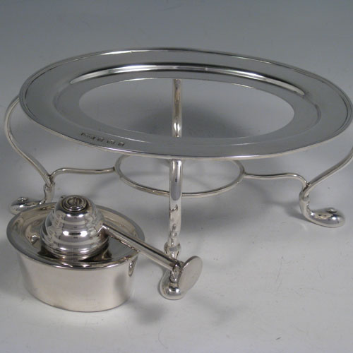 Sterling silver tea kettle on a burner stand, having a very plain oval straight-sided body, with hinged lid, insulated wooden handle and finial, and sitting on an original burner stand with four scroll feet. Made by Daniel and Arter of Birmingham in 1917. The dimensions of this fine silver kettle are length 23 cms (9 inches), height 26 cms (10.25 inches), width 15 cms (6 inches), and the total weight is approx. 1,085g (35 troy ounces).