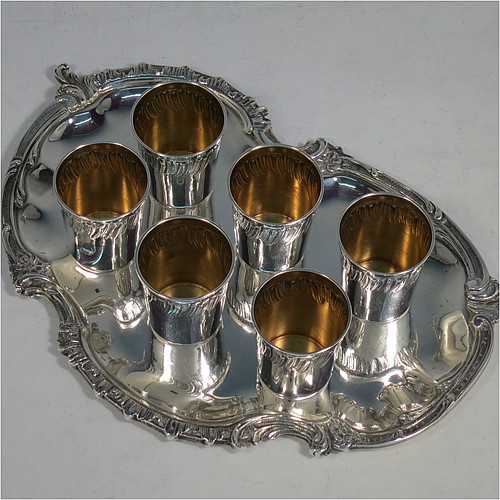 An Antique Victorian French First Quality Standard (950 std) sterling silver set of six liqueor tots / measures and original serving salver, the tots having round straight-sided bodies with gold-gilt interiors and hand-chased swirl-fluted upper borders, the salver with a plain ground and an applied cast foliate border. Made in France in ca. 1890. The dimensions of this fine hand-made antique silver liqueur set are height of tots 4 cms (1.5 inches), length of serving tray 20 cms (8 inches), and the total weight is approx. 285g (9.2 troy ounces).   