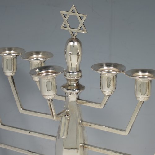 A Sterling Silver Hanukkah Menorah in an Art Deco style, having an octagonal panelled body sitting on a pedestal foot, with a removable Shamus candle holder. Made in Birmingham in 1948. The dimensions of this fine hand-made silver menorah are height 23 cms (9 inches), spread across arms 25 cms (9.75 inches), and it weighs approx. 248g (8 troy ounces) Please note that this item is not filled so the whole weight is silver.    