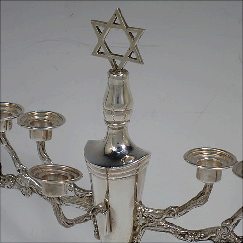 A pretty Sterling Silver Hanukkah Menorah, having a neoclassical style plain oval urn-shaped main body sitting on a pedestal foot, with cast grapevine style arms, and a removable Shamus candle holder. Made by D. J. Silver of London in 1970. The dimensions of this fine hand-made silver menorah are height 21 cms (8.25 inches), and spread across arms 26 cms (10.25 inches).   