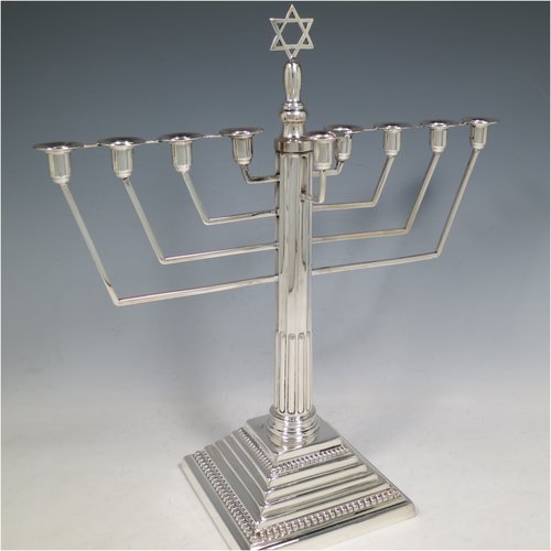 A Sterling Silver Menorah, having a Corinthian style body with a fluted column, and a stepped base with bead borders. Made in Birmingham in 1938. The dimensions of this fine hand-made silver menorah are height 33 cms (13 inches), spread across arms 30.5 cms (12 inches), and it weighs approx. 458g (14.8 troy ounces) Please note that this item is not filled.   