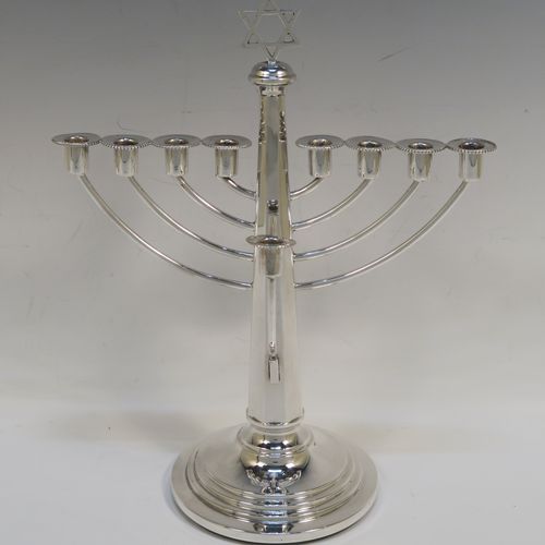 A very elegant Sterling Silver Hanukkah Menorah in a traditional style with rounded wire-work arms, having an octagonal panelled body with tapering sides, an original removable Shamus candle holder, and all sitting on a round stepped pedestal foot. This handsome silver menorah was made in Birmingham in 1957. The dimensions of this fine hand-made silver menorah are height 26 cms (10.25 inches), and spread across arms 21 cms (8.25 inches).   